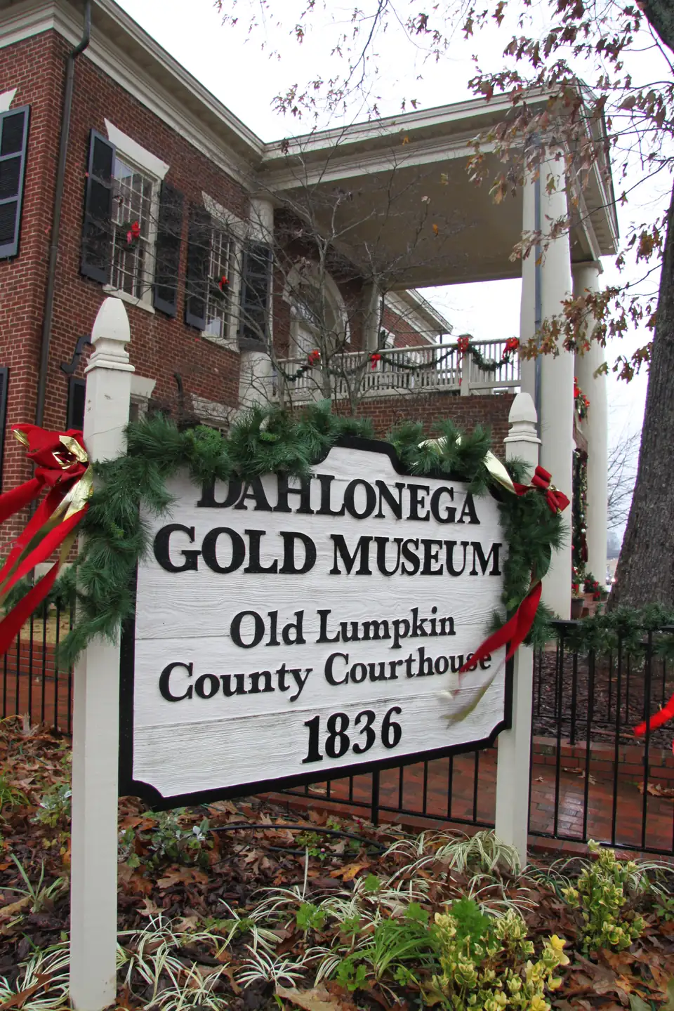 The Dahlonega Gold Museum sign wrapped in holiday garland and red bows.