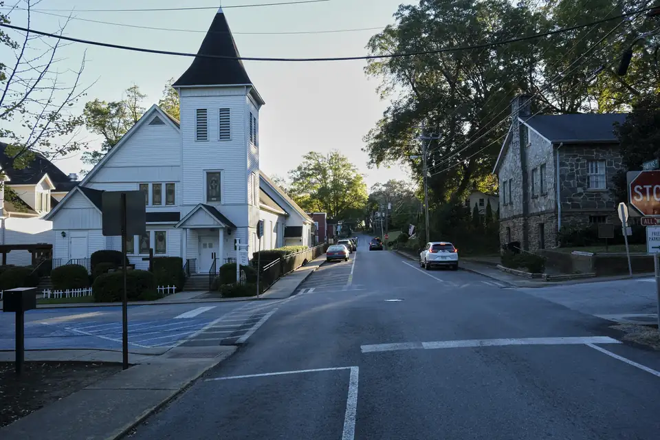 North Park Street climbing away from the Hawkins Street crossing, with a white steepled church on one side and a stone community house on the other.