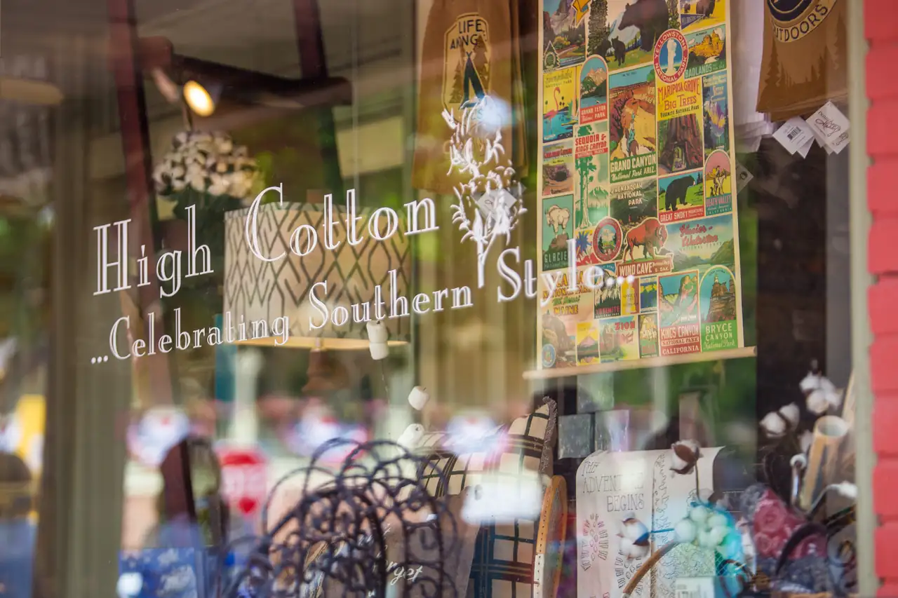 The window of High Cotton, a gift shop lettered 'Celebrating Southern Style', full of cotton stems, pillows and a national-parks poster.