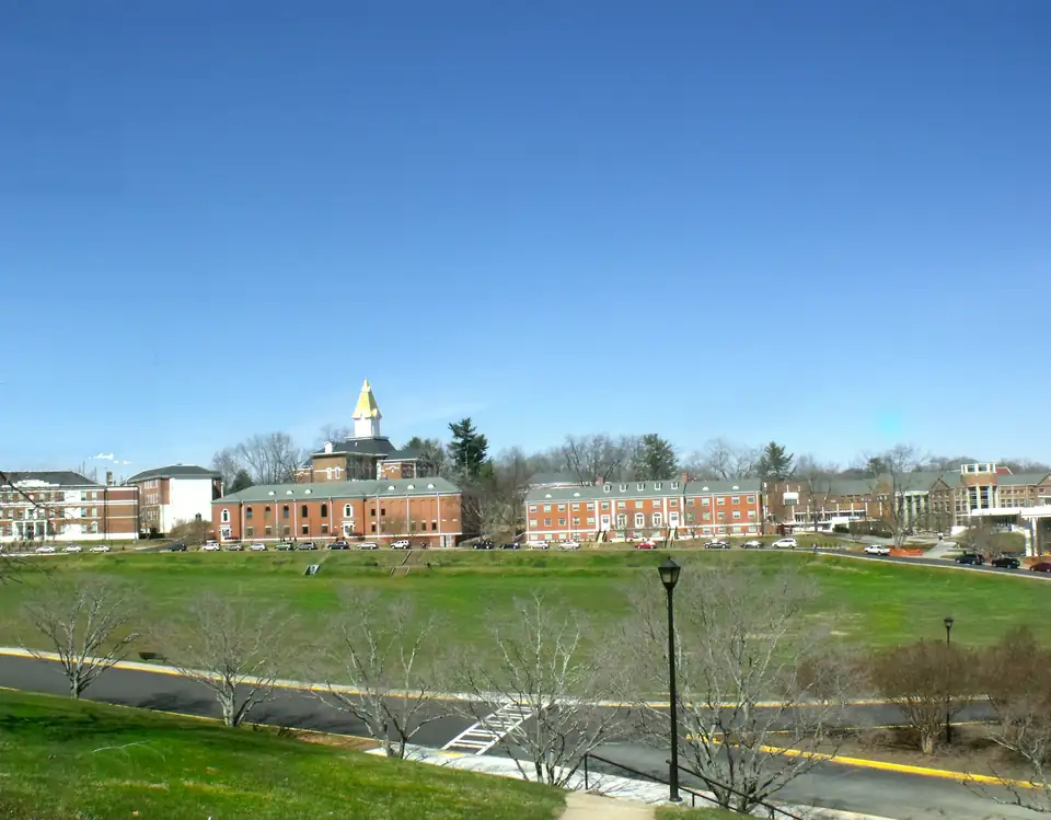 The University of North Georgia campus in Dahlonega, with a gold-topped steeple rising above red-brick halls across a broad green field.